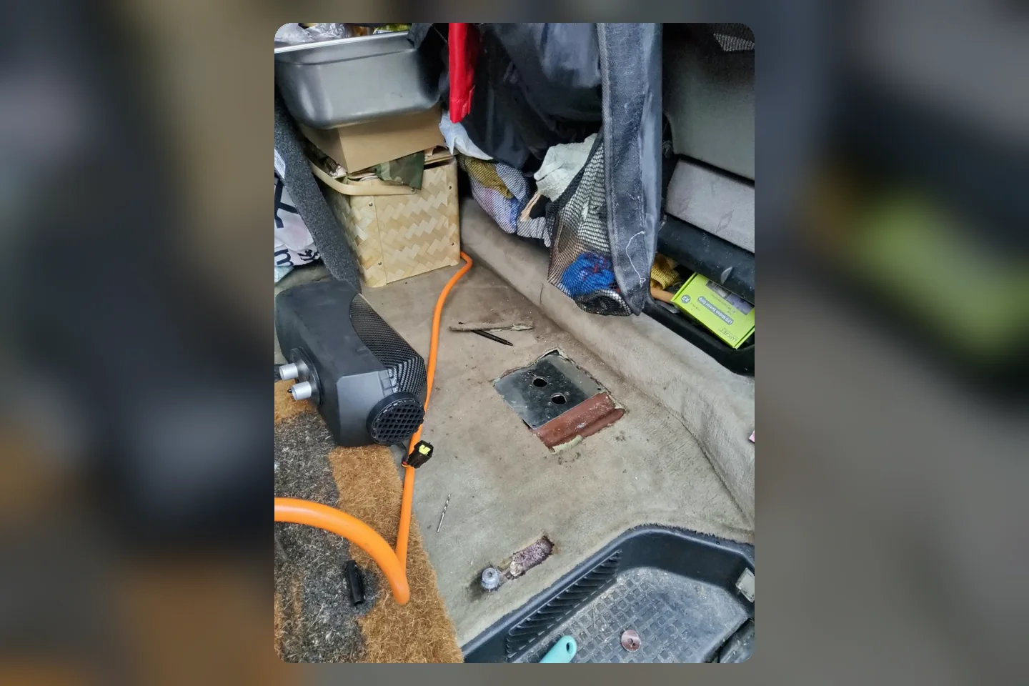 Blick in den roten T4 während des Einbaus einer Dieselheizung mit geöffnetem Bodenzugang und orangefarbener Leitung